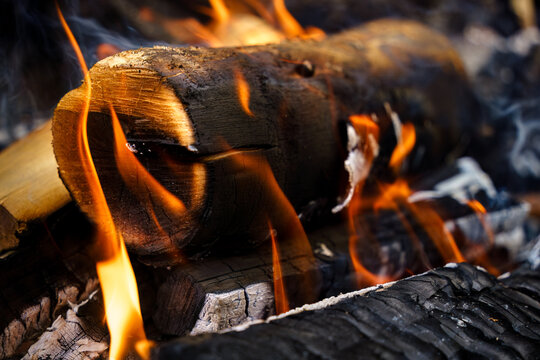 Burning log surrounded by flames in a campfire