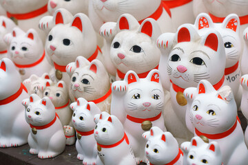 Tokyo, Japan - Sep 30 2024, A close-up view of many multi-sized white beckoning cat figure of Maneki neko with red ears and noses displayed at Gotokuji Temple, without people, at daytime, Tokyo, Japan