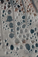 Water droplets gather on a surface covered in fine textures