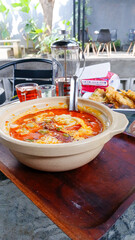 Spicy Asian soup served in a clay pot, filled with fresh red broth, soft tofu, vegetables, and chili oil. Culinary concept, restaurant, or traditional food.
