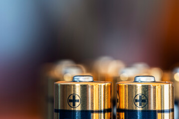 Close-up of AA alkaline batteries standing upright with a blurred industrial background