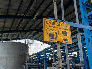 Yellow emergency shower and eye wash sign in the chemical industry area. Wash the part that is exposed to the chemical