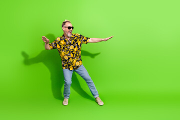 Energetic man in tropical print shirt enjoying vibrant green background showcasing summer style and...