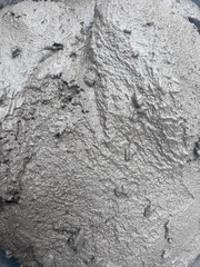 The cement looks freshly mixed, likely still in the process of setting or being prepared for pouring or shaping. The color is a typical grayish hue associated with cement or concrete.