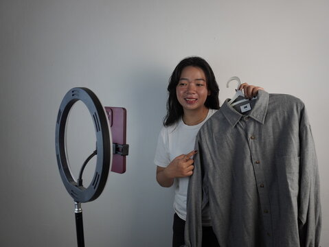 Social market concept. Young Asian woman live streaming selling clothes in the mobile application