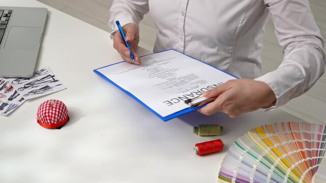 Person Signing an Insurance Document with a Blue Pen