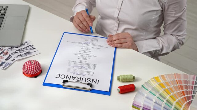 Person Signing an Insurance Document with a Blue Pen