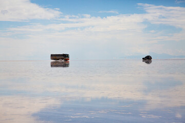 Iconic 4x4 vehicles traversing the mirrored surface of Salar de Uyuni, Bolivia. Witness the surreal beauty of the world's largest salt flat, a prime ecotourism adventure