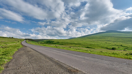 Scenic road winding through green fields and hills