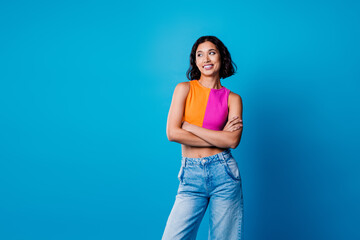 Charming young woman in stylish casual outfit posing against a vibrant blue background with an...