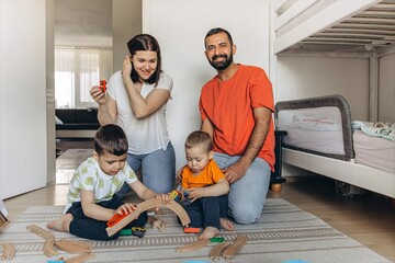 Parents playing and laughing with their two sons in a bright children room. Family bonding, playful...