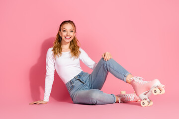 Beautiful young woman in casual attire sitting on a pink background smiling with a cheerful and...