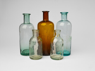 Vintage apothecary glass jars in a row close-up on white background. Antique colored glassware 