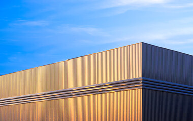 Warehouse factory building with golden sunlight on gray aluminium corrugated steel wall against...