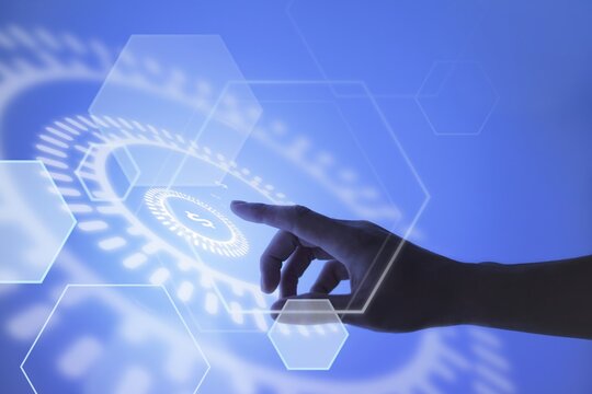 Hand touching holographic interface with hexagons and circular design on blue