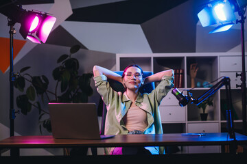 Young professional enjoying a creative workspace with modern lighting, engaged in work or streaming...