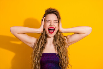 Young cheerful woman in a flashy dress expressing joy against a vibrant yellow backdrop, showcasing...