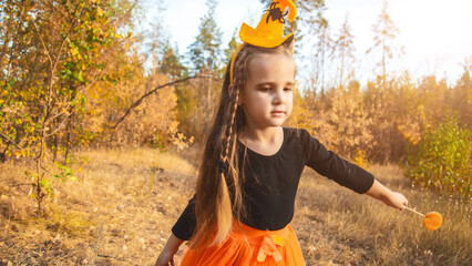 Little girl in scary witch costume at halloween celebrations party in forest. Halloween -...