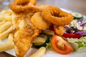 Fish and Chips salad with fried onion ring, served on plate