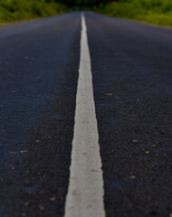 Long, empty asphalt road stretches ahead with a single white line.