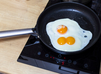 Fried eggs on the pan one of them with double egg egg yolk. Food
