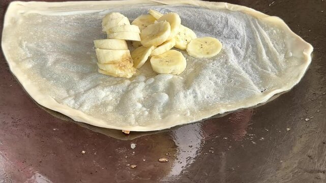 4k Street food vendor is preparing the dough and pan-frying paratha roti in hot oil until crispy on the outside. Street hawker preparing prata bread or roti canai for morning break