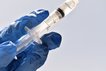 Doctor holding a 5 ml syringe in blue medical gloves. Sterile preparation for injection,...