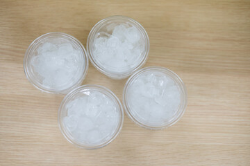 Top view of ice in a clear plastic glass on wood table