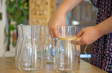 Professional florist arranging rustic blooms, wrapping jute twine around clear glass vessels, creating sustainable botanical design