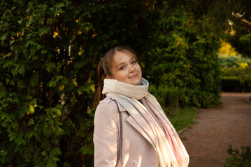 Pretty young girl wearing light coat in the autumn park