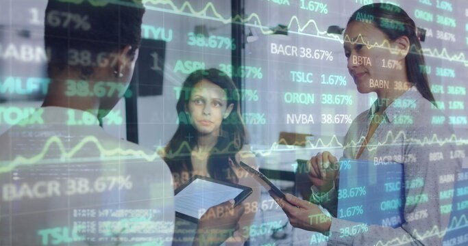 Analyzing three women reviewing data on tablet and smartphone in office, with stock chart overlay
