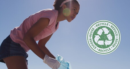 Image of recycling symbol over african american woman cleaning at beach