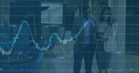 Image of graph data moving over multiracial partners discussing with tablet in office lobby