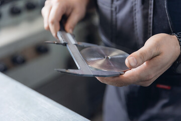 Worker measuring metal disc with caliper in industrial factory setting