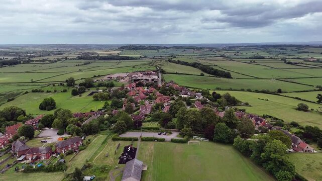 Aerial view of Ashendon village surrounded by green fields under cloudy sky in Buckinghamshire