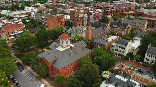 Front-facing aerial drone shot of downtown Frederick, Maryland. Shows historic buildings, streets, and city layout on a clear day.