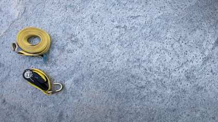Yellow ratchet straps resting on concrete surface, securing heavy loads during transportation, highlighting professional cargo handling equipment. Copy space
