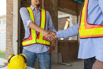 Construction workers shake hands at a job site during a project meeting