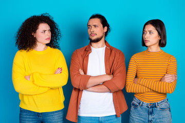Casual group of three young adults in colorful outfits against a blue background expressing skeptical attitudes