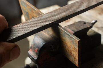 A mechanic is grinding a part with a file.