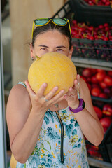 Mature woman choosing ripe melon in street shop in resort town. Summer healthy shopping in farm...