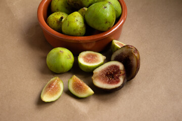 Fresh Figs in a Terracotta Bowl with Halved and Whole Pieces on Brown Surface