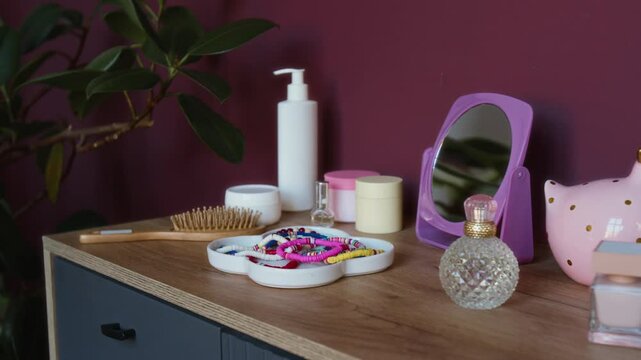 Close-up no people shot of toiletries, colorful bracelets, and mirror on dresser in cozy teenage girl bedroom