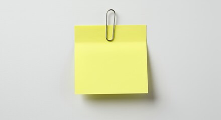 Yellow sticky note with paperclip on white background