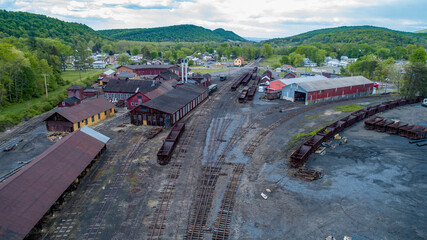 An expansive view of a historic train yard featuring multiple rail tracks and warehouses nestled in...