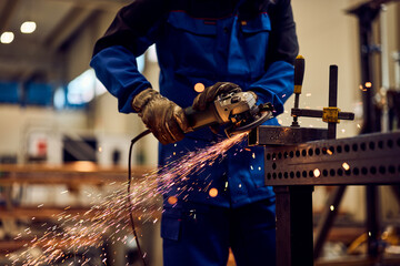 Industrial Worker Using Grinder Tool with Bright Sparks Emitting During Metalwork