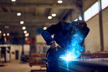 Welder Working in an Industrial Factory Creating Sparks with Protective Gear