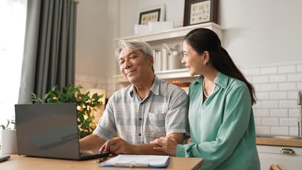 Grandmother comforting and supporting grandfather while looking at laptop show successful project...