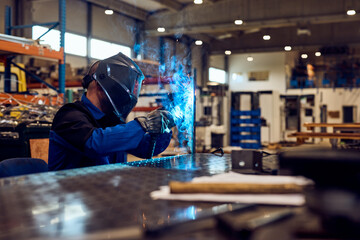 Welder Working in a Workshop with Sparks and Safety Equipment