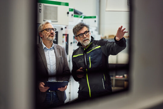 Two Engineers Collaborating Inside an Industrial Facility with Equipment in the Background